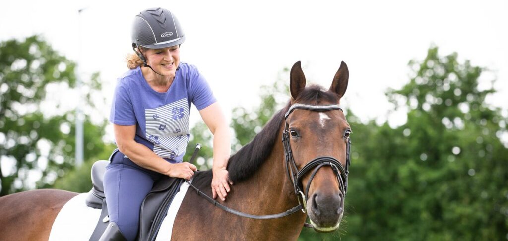 Evi Ansems die een paard beloont